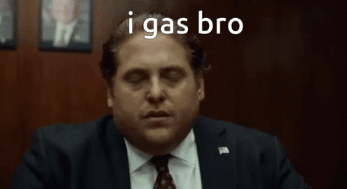 A Man In A Suit And Tie Is Sitting In Front Of A Wooden Wall With His Eyes Closed . GIF