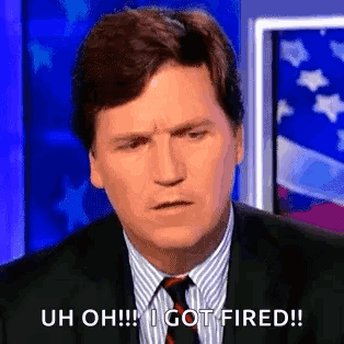A Man In A Suit And Tie Is Sitting In Front Of An American Flag And Making A Funny Face . GIF