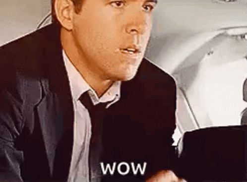 A Man In A Suit And Tie Is Sitting In The Back Seat Of A Plane . GIF