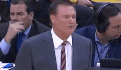 A Man In A Suit And Tie Is Sitting In The Stands Watching A Game . GIF