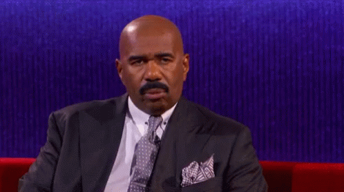 A Man In A Suit And Tie Is Sitting On A Couch GIF