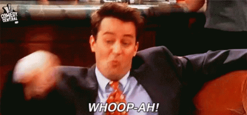 A Man In A Suit And Tie Is Sitting On A Couch With His Arms Outstretched And Saying Whoop-Ah . GIF