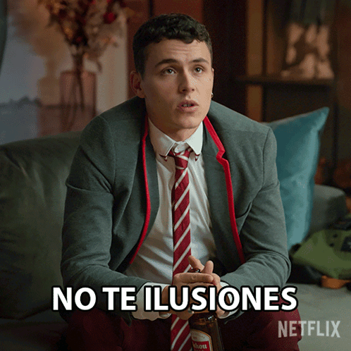 A Man In A Suit And Tie Is Sitting On A Couch With The Words No Te Ilusiones Written On The Screen GIF
