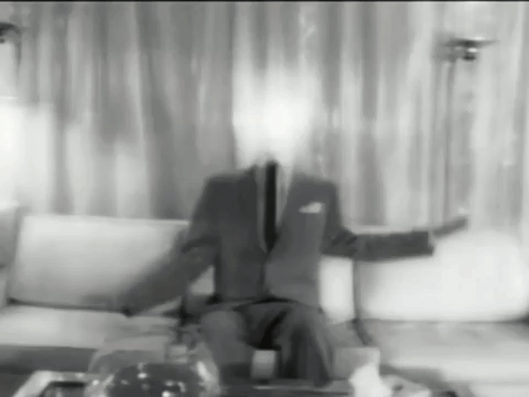 A Man In A Suit And Tie Is Sitting On A Couch Without A Face GIF
