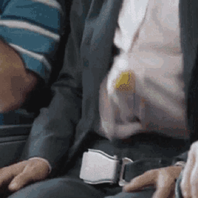 A Man In A Suit And Tie Is Sitting On A Plane GIF