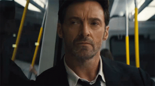 A Man In A Suit And Tie Is Sitting On A Train GIF
