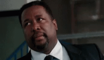 A Man In A Suit And Tie Is Sitting With His Eyes Closed And His Mouth Open . GIF
