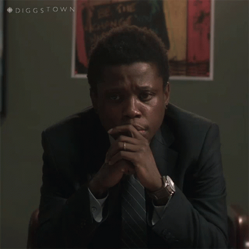 A Man In A Suit And Tie Is Sitting With His Hands Folded In Front Of A Poster That Says Diggstown GIF
