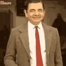 A Man In A Suit And Tie Is Smiling . GIF