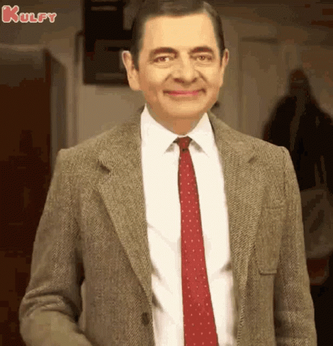 A Man In A Suit And Tie Is Smiling . GIF