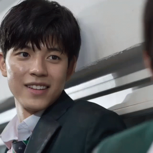 A Man In A Suit And Tie Is Smiling And Looking At The Camera GIF