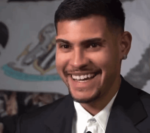 A Man In A Suit And Tie Is Smiling And Looking To The Side GIF