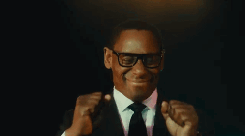 Man In Suit And Tie Smiling And Fist Pumping GIF