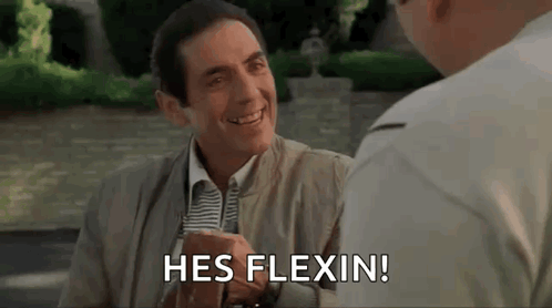 A Man In A Suit And Tie Is Smiling And Talking To Another Man While Sitting At A Table . GIF