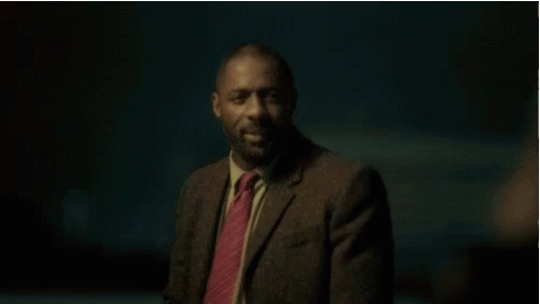 A Man In A Suit And Tie Is Smiling At Someone GIF
