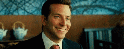 A Man In A Suit And Tie Is Smiling . GIF