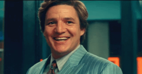 A Man In A Suit And Tie Is Smiling For The Camera GIF