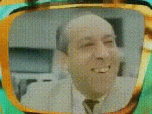 A Man In A Suit And Tie Is Smiling In A Television Screen . GIF