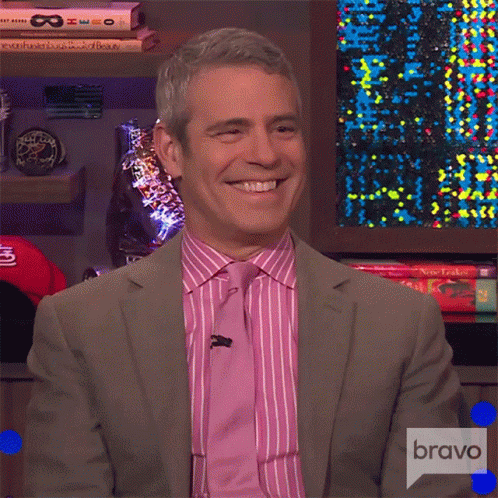 Smiling Man In Suit In Front Of Bravo Sign GIF