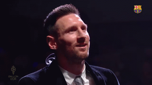 a man in a suit and tie is smiling in front of a sign that says ballon dor