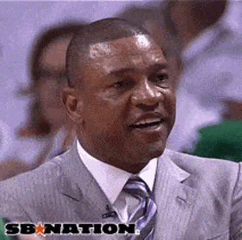 A Man In A Suit And Tie Is Smiling In Front Of A Sign That Says Sbnation GIF