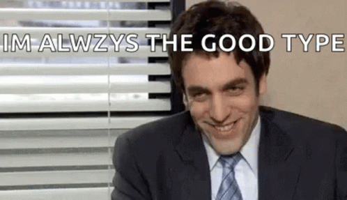 A Man In A Suit And Tie Is Smiling In Front Of A Window With Blinds . GIF