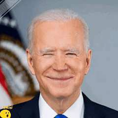 A Man In A Suit And Tie Is Smiling In Front Of An American Flag . GIF