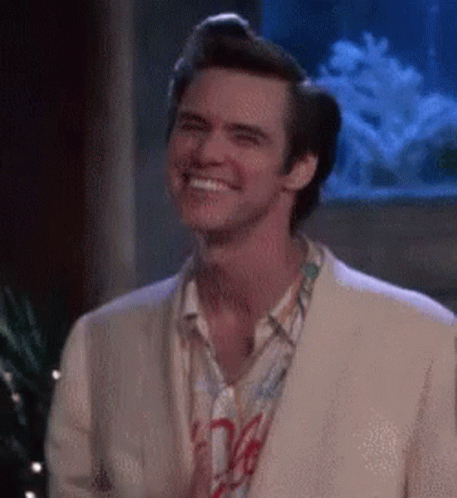 A Man In A Suit And Tie Is Smiling In Front Of An Aquarium . GIF