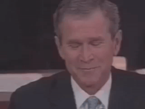 A Man In A Suit And Tie Is Smiling . GIF