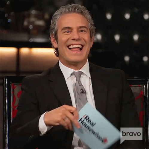 a man in a suit and tie is smiling while holding a real housewives card