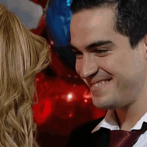 a man in a suit and tie is smiling while looking at a woman