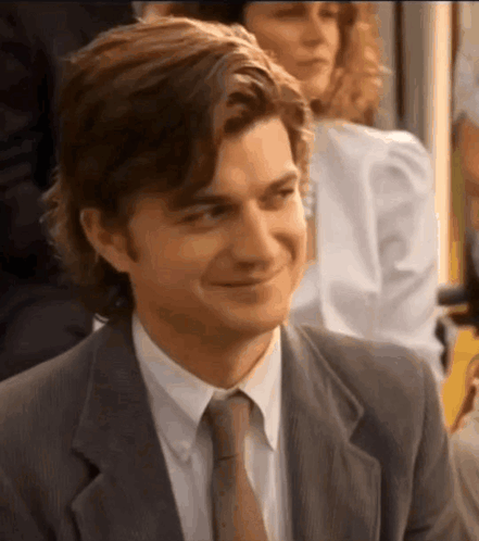 A Man In A Suit And Tie Is Smiling While Sitting In A Room . GIF