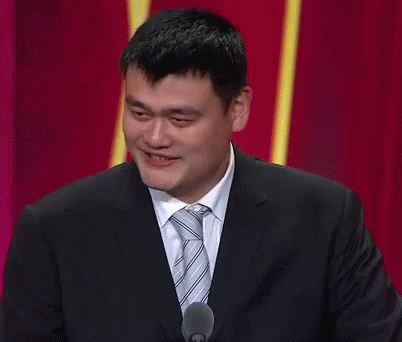 A Man In A Suit And Tie Is Smiling While Speaking Into A Microphone GIF