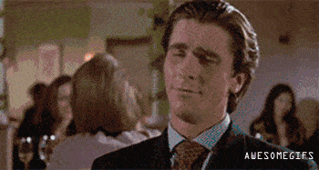 A Man In A Suit And Tie Is Smiling While Standing In A Crowded Room . GIF