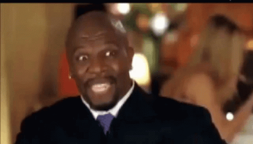 A Man In A Suit And Tie Is Smiling While Standing In Front Of A Group Of People . GIF