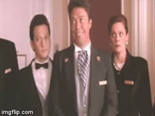 A Man In A Suit And Tie Is Smiling While Standing Next To A Woman In A Suit . GIF