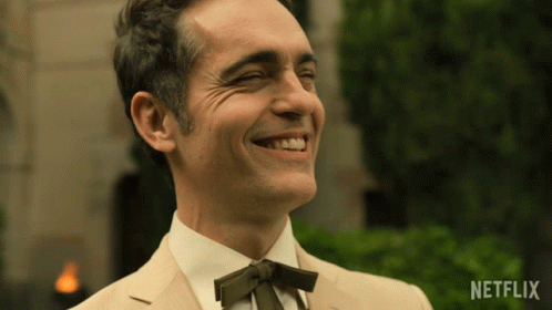 A Man In A Suit And Tie Is Smiling With A Netflix Logo On The Bottom Right GIF