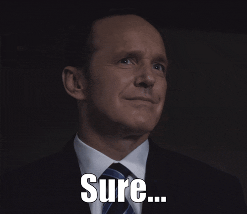A Man In A Suit And Tie Is Smiling With The Word Sure Below Him GIF