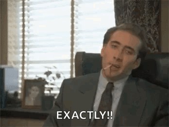 A Man In A Suit And Tie Is Smoking A Cigarette In An Office . GIF