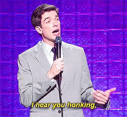 A Man In A Suit And Tie Is Speaking Into A Microphone And Says I Hear You Honking GIF