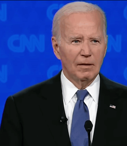 A Man In A Suit And Tie Is Speaking Into A Microphone In Front Of A Cnn Background GIF