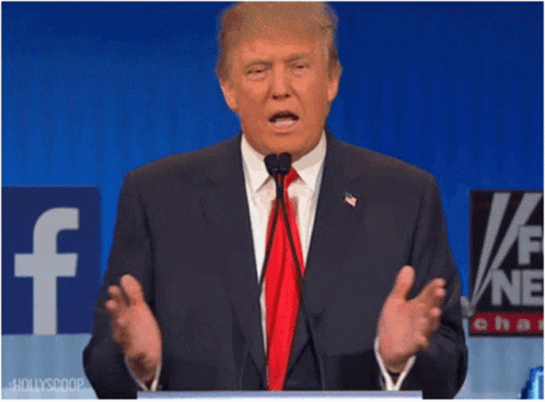 A Man In A Suit And Tie Is Speaking Into A Microphone In Front Of A Facebook Sign GIF