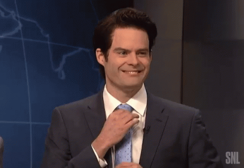 A Man In A Suit And Tie Is Speaking Into A Microphone With The Snl Logo In The Background GIF