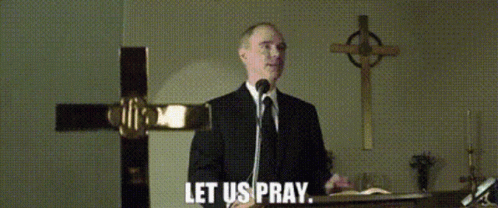 A Man In A Suit And Tie Is Speaking Into A Microphone With The Words Let Us Pray Below Him GIF