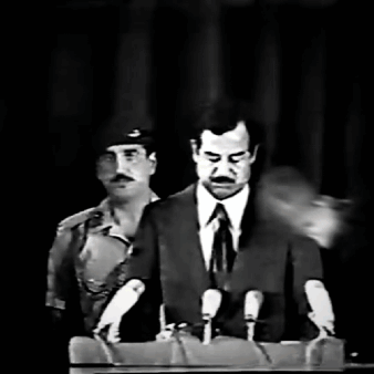 A Man In A Suit And Tie Is Speaking Into Microphones GIF