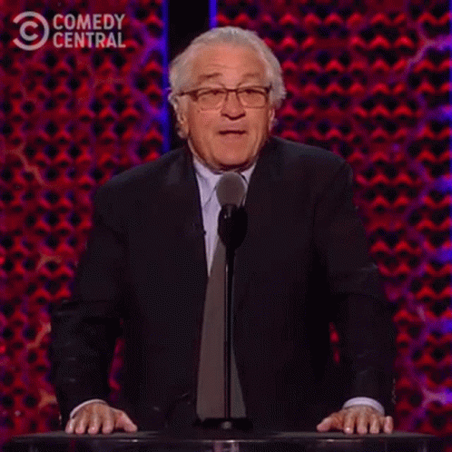 A Man In A Suit And Tie Is Standing At A Podium Giving A Speech And Saying `` Not One '' . GIF