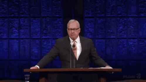 a man in a suit and tie is standing at a podium giving a speech and the word liar is above him .
