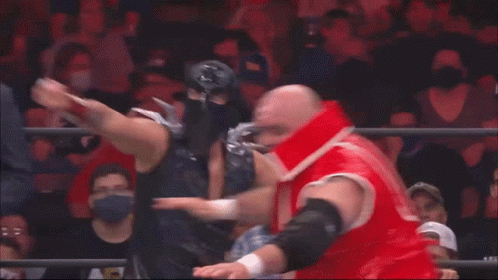 a man in a suit and tie is standing behind two wrestlers