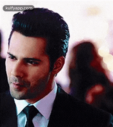 A Man In A Suit And Tie Is Standing In A Crowd . GIF