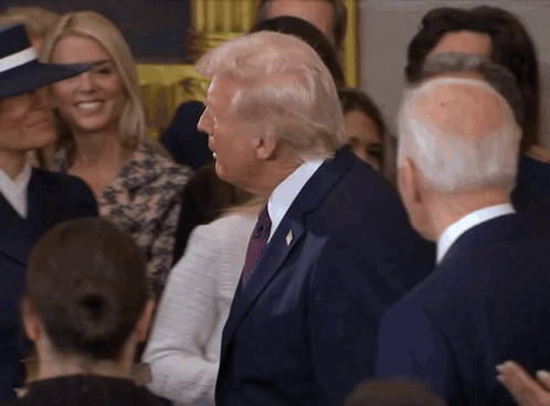 A Man In A Suit And Tie Is Standing In A Crowd GIF